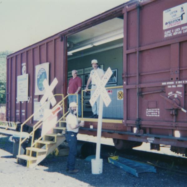 Photograph of exterior of Conrail Safety on Rails Theater boxcar 368191 and crew at Port Jervis, NY, July 1996