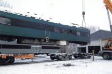 Color photograph of Milwaukee Road passenger car being lifted by crane in Charles City, Iowa, circa 2012