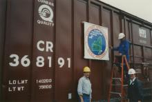 Photograph of exterior of Conrail Safety on Rails Theater boxcar 368191 with Philadelphia Division safety logo being installed, Oak Island Yard, Newark, NJ, summer 1992
